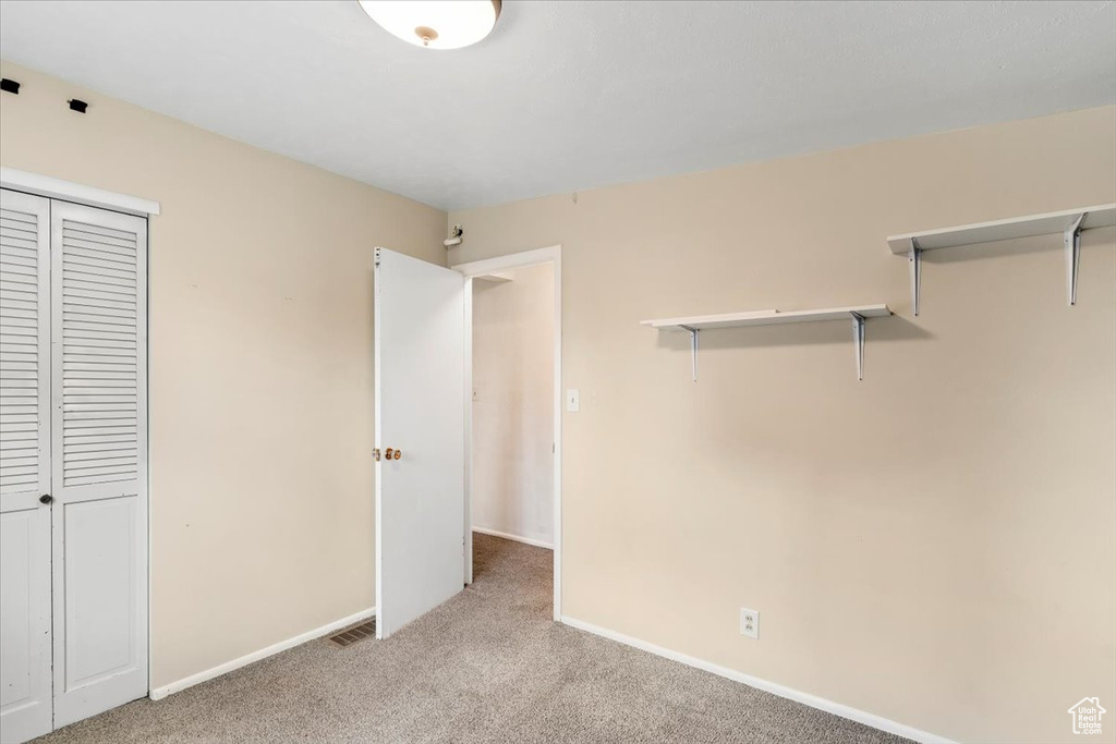 Unfurnished bedroom featuring light carpet, baseboards, and a closet