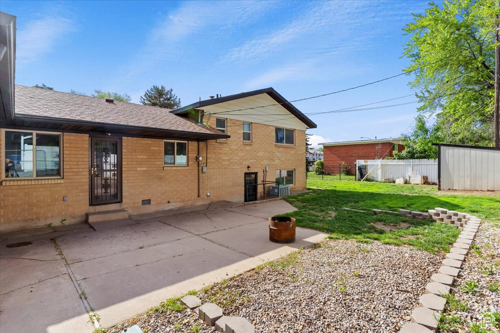 Rear view of property featuring brick siding, central AC, a patio area, and a shingled roof