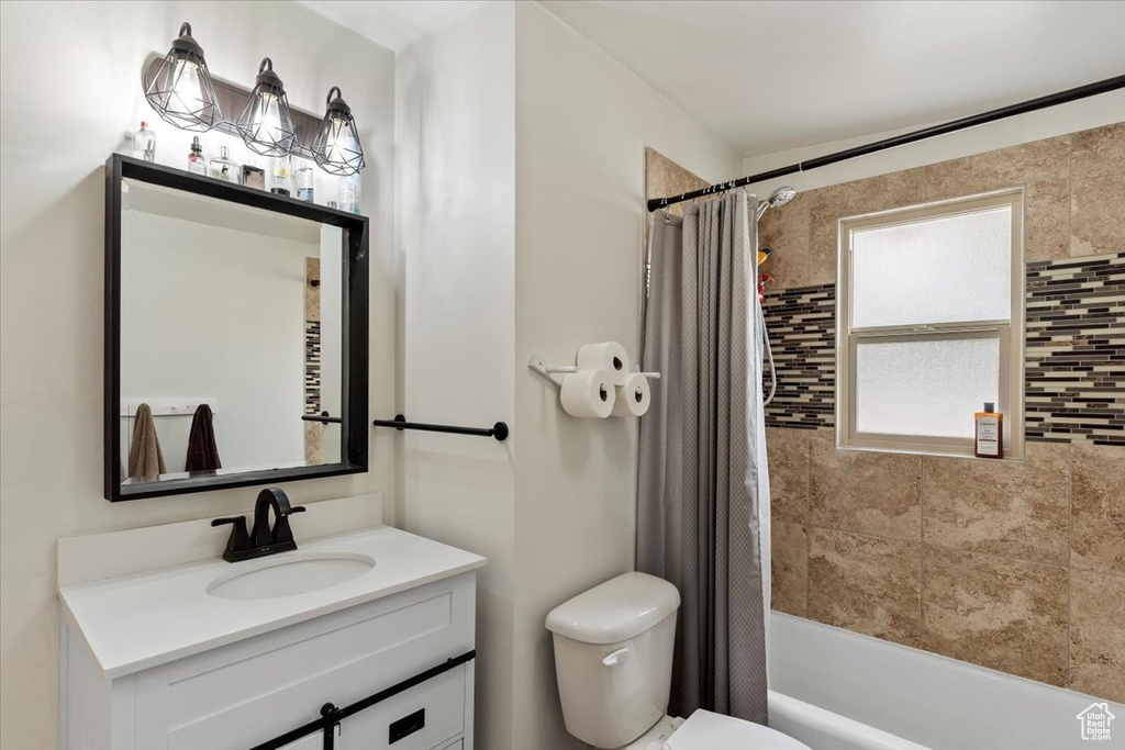 Bathroom with toilet, vanity, and shower / bath combination with curtain