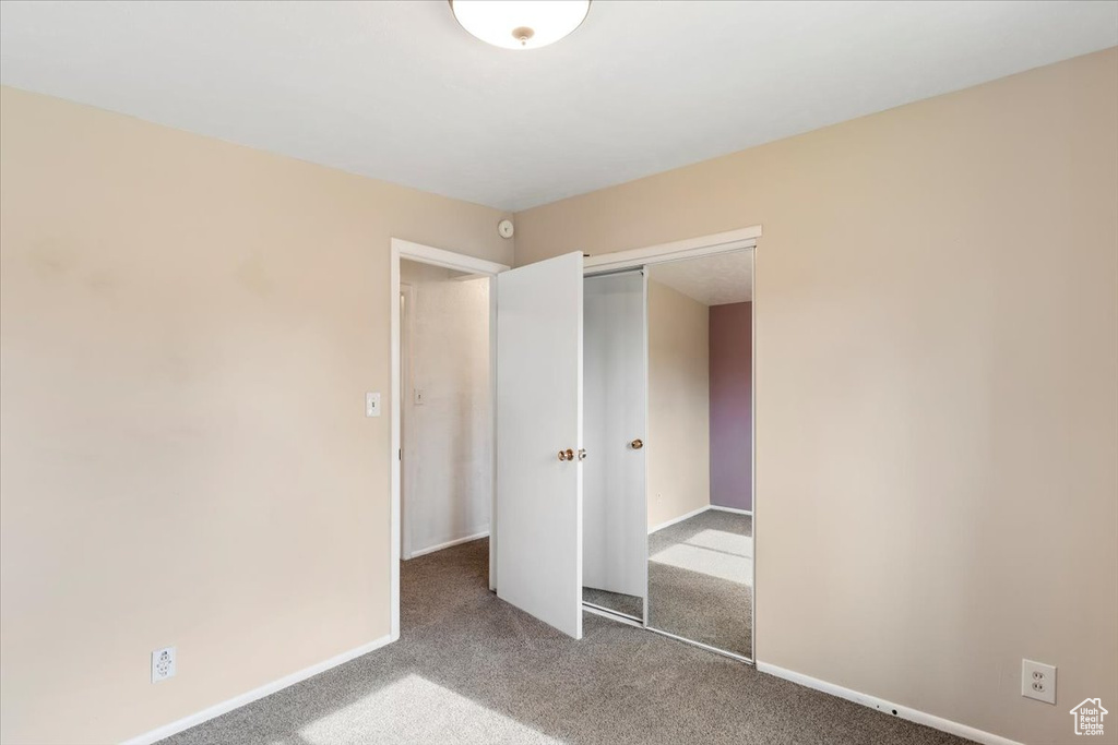 Unfurnished bedroom featuring carpet, a closet, and baseboards