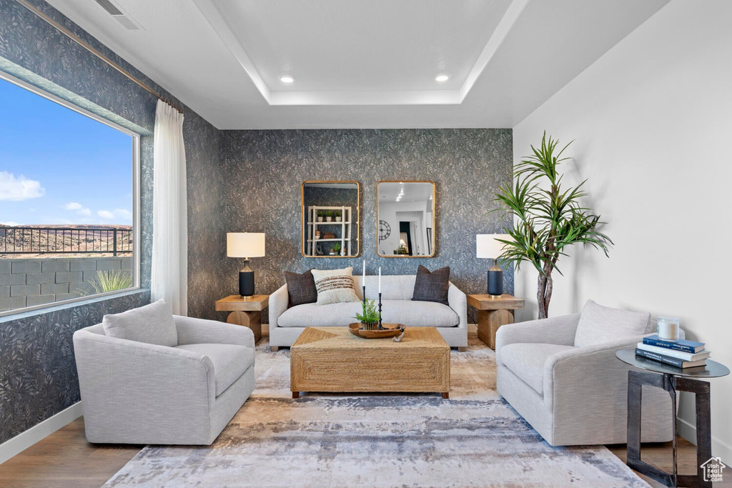 Living area with wood finished floors, recessed lighting, a tray ceiling, and baseboards