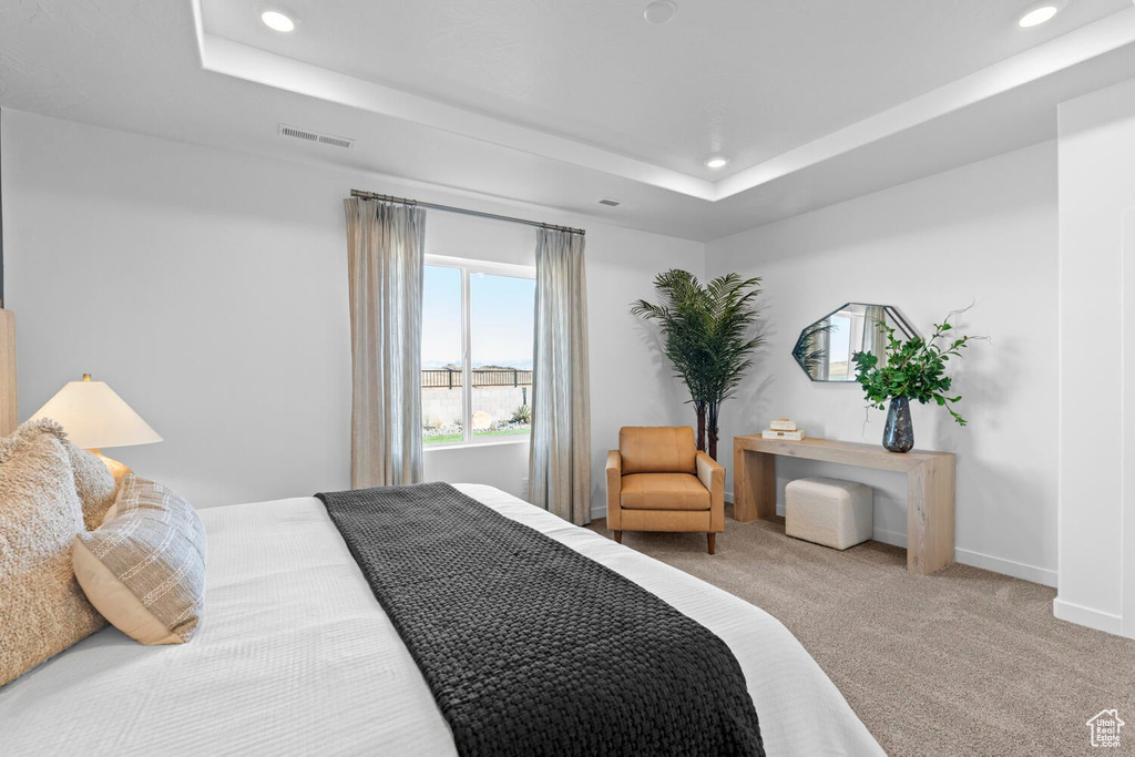 Carpeted bedroom featuring recessed lighting, a tray ceiling, and baseboards