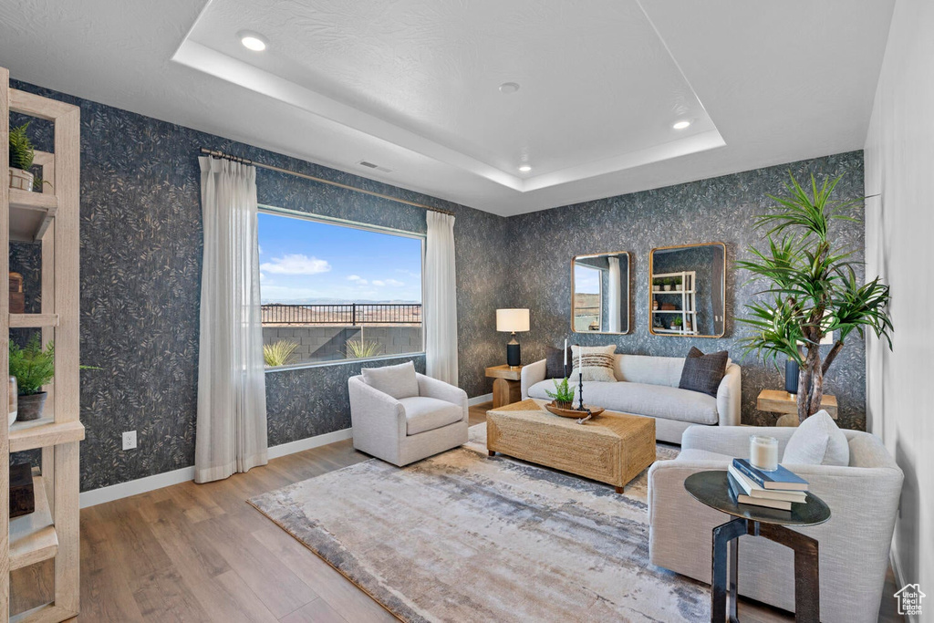 Living area featuring a tray ceiling, wood finished floors, recessed lighting, wallpapered walls, and baseboards