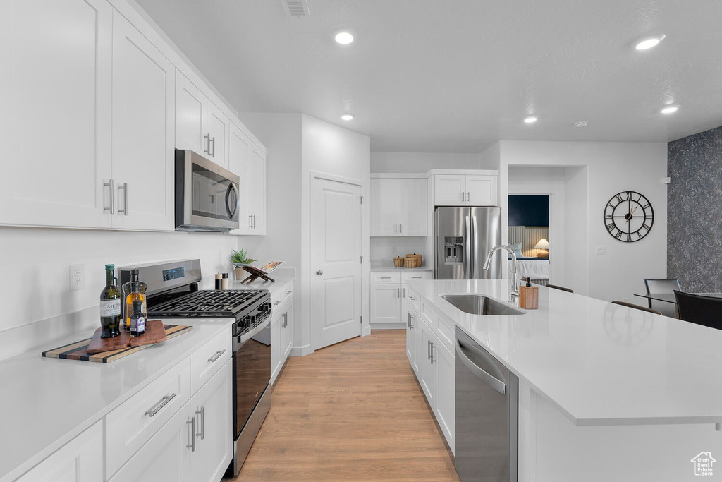Kitchen featuring stainless steel appliances, a sink, recessed lighting, light countertops, and light wood-style floors