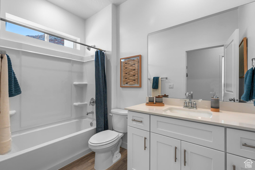 Full bath with wood finished floors, toilet, vanity, and shower / bathtub combination with curtain
