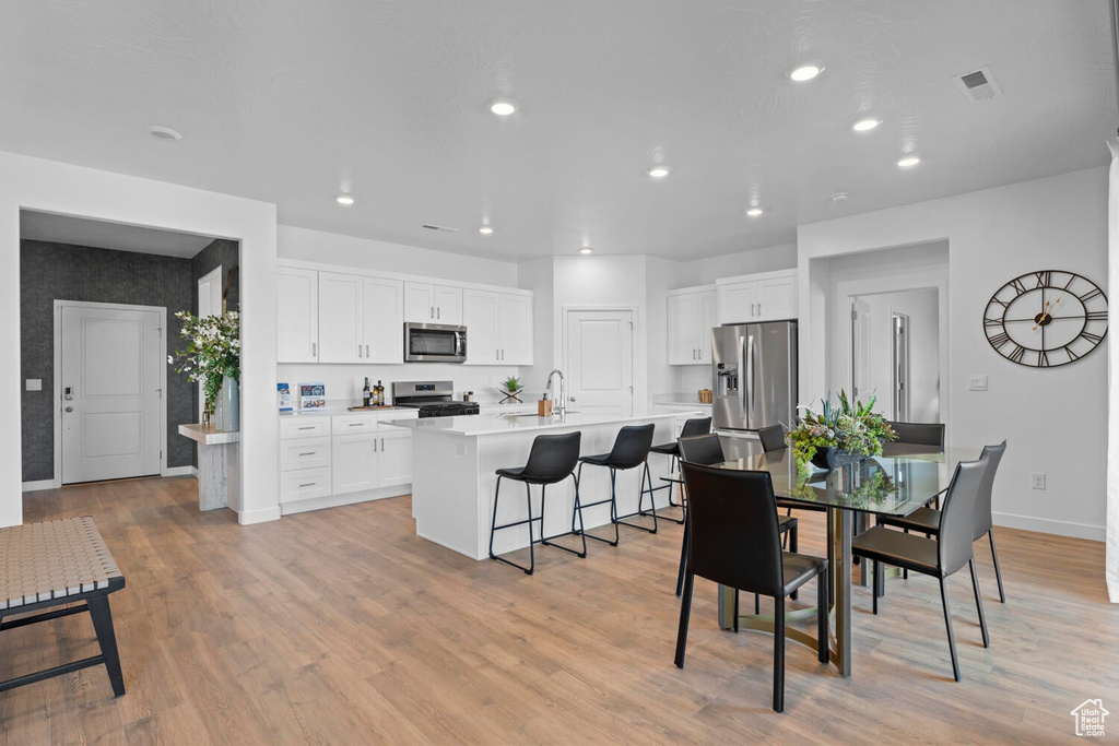 Dining area featuring baseboards, light wood-style flooring, and recessed lighting