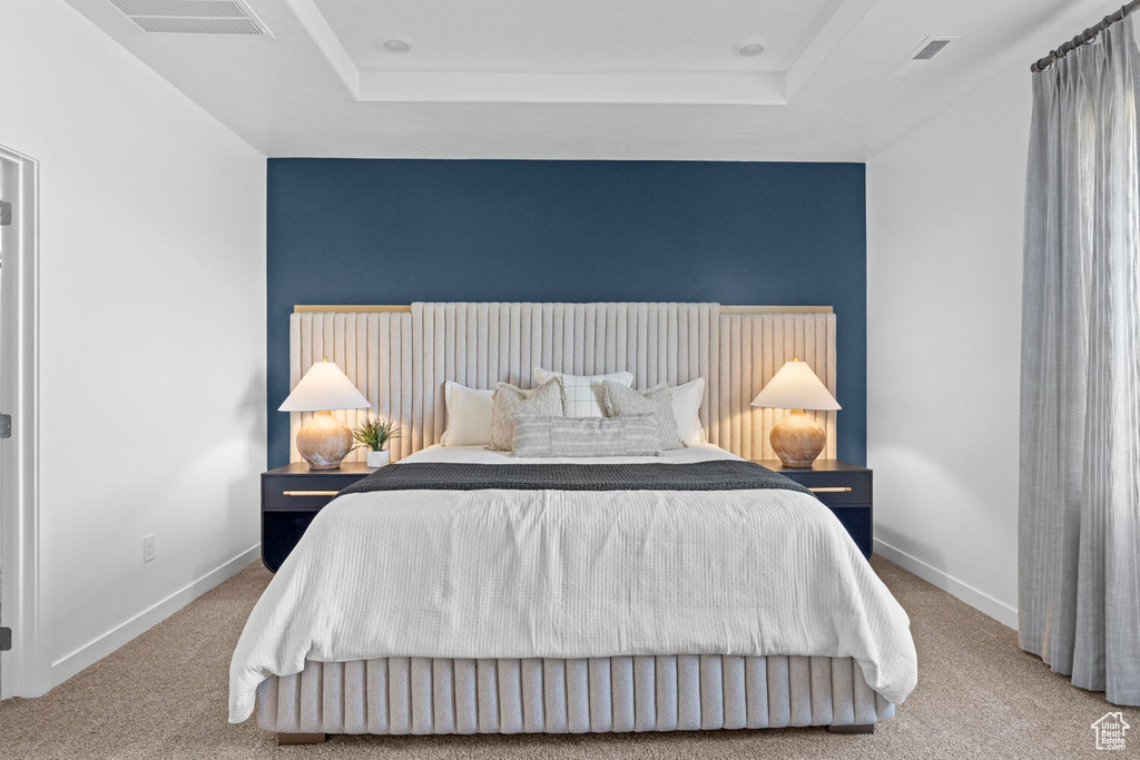 Bedroom with carpet floors, a tray ceiling, and baseboards