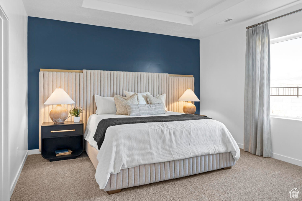 Bedroom with carpet floors, baseboards, and a tray ceiling