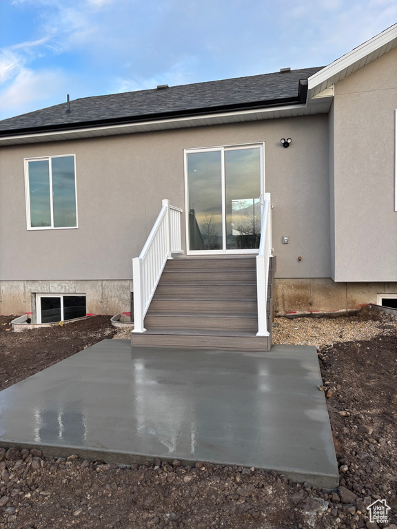 Property entrance featuring roof with shingles and stucco siding