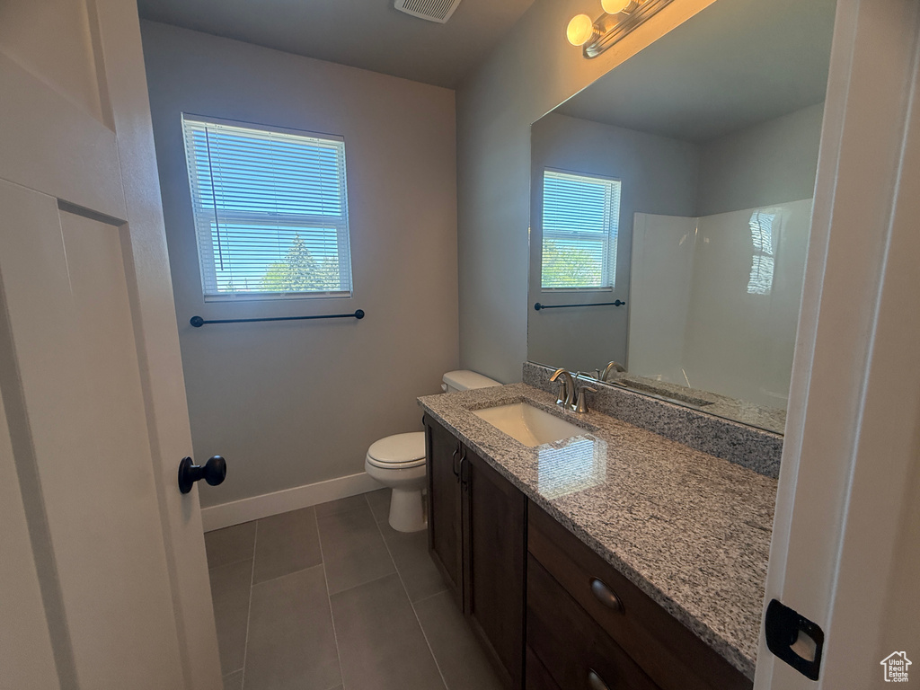 Full bathroom with toilet, tile patterned flooring, vanity, a shower, and baseboards