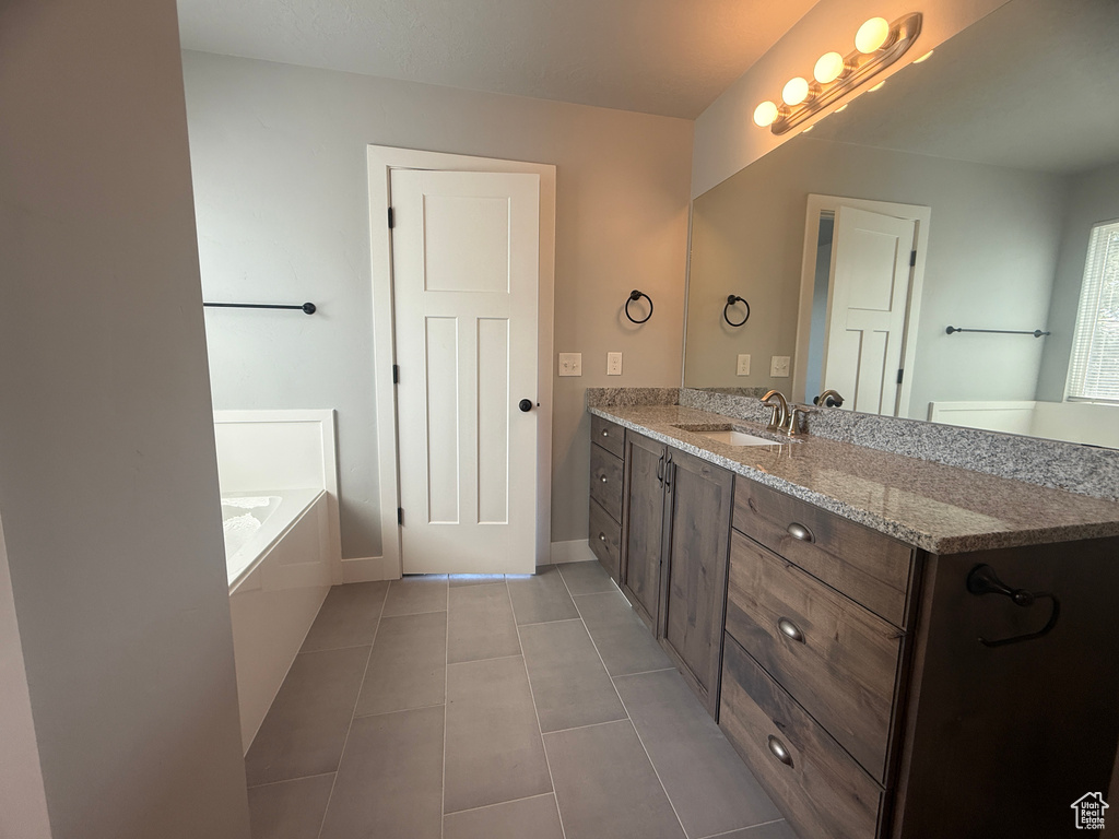 Bathroom with vanity, tile patterned floors, a bath, and baseboards