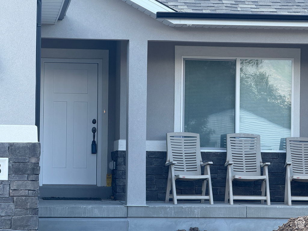 Entrance to property with stucco siding and a shingled roof