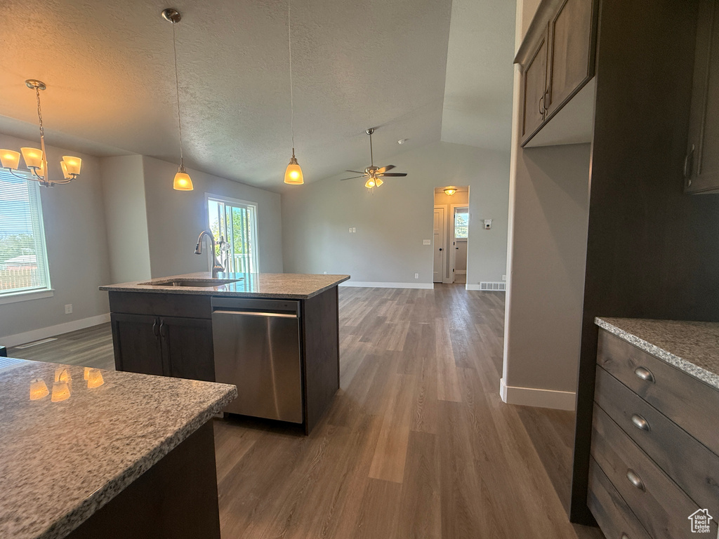 Kitchen with stainless steel dishwasher, a sink, dark wood finished floors, vaulted ceiling, and baseboards