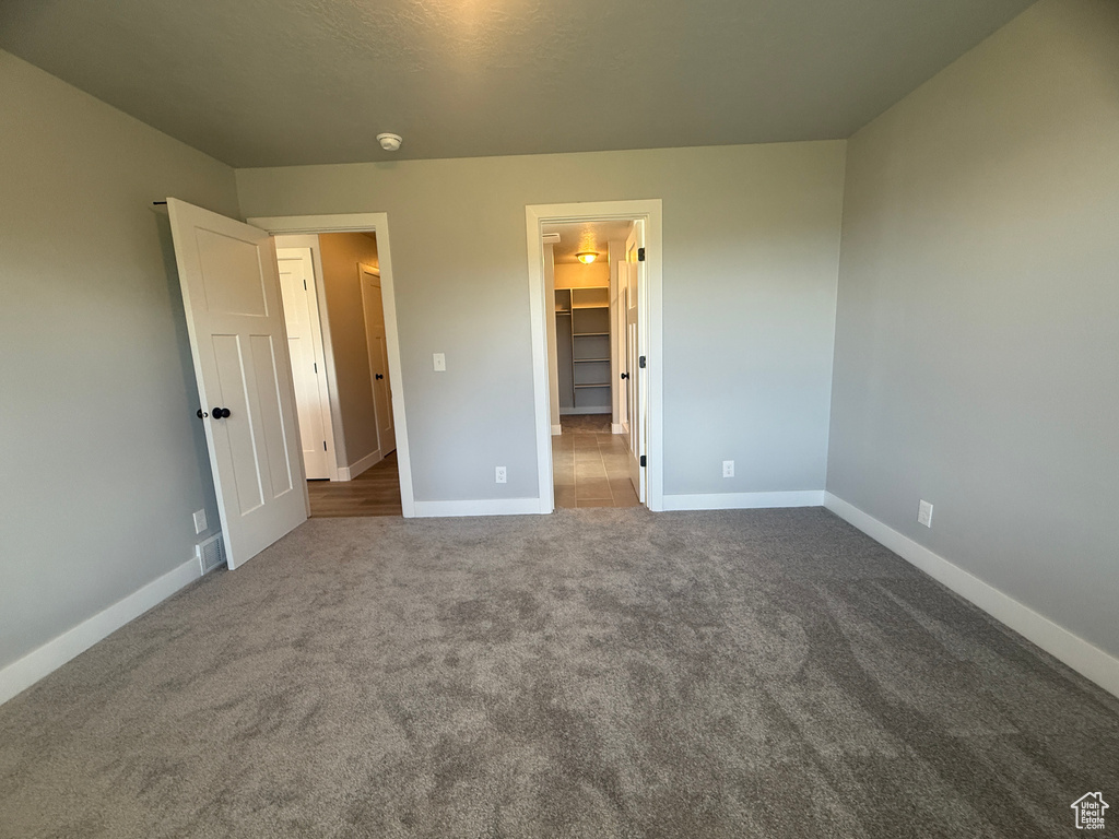Unfurnished bedroom featuring baseboards, carpet, and a spacious closet