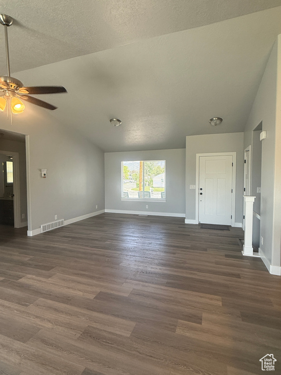 Unfurnished living room with lofted ceiling, baseboards, dark wood-style floors, a ceiling fan, and a textured ceiling