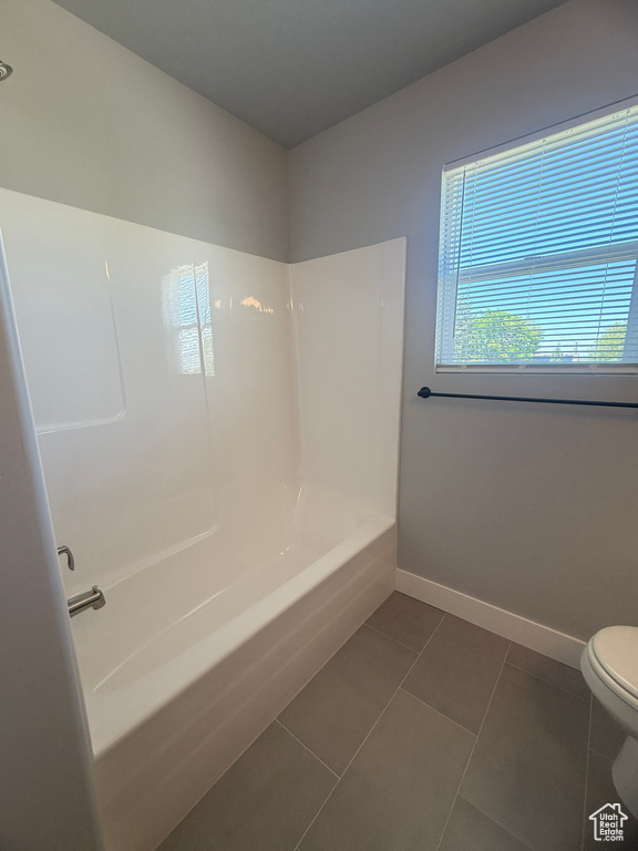 Bathroom featuring toilet, baseboards, tile patterned floors, and shower / washtub combination
