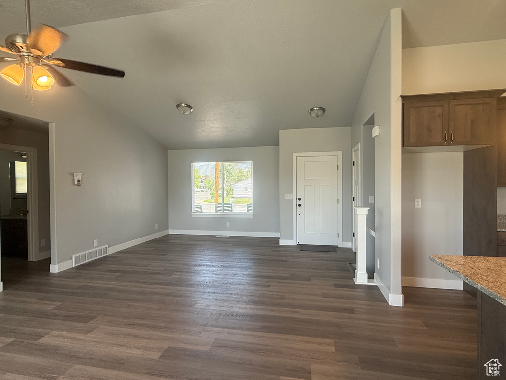Unfurnished living room featuring vaulted ceiling, baseboards, ceiling fan, and dark wood-style flooring
