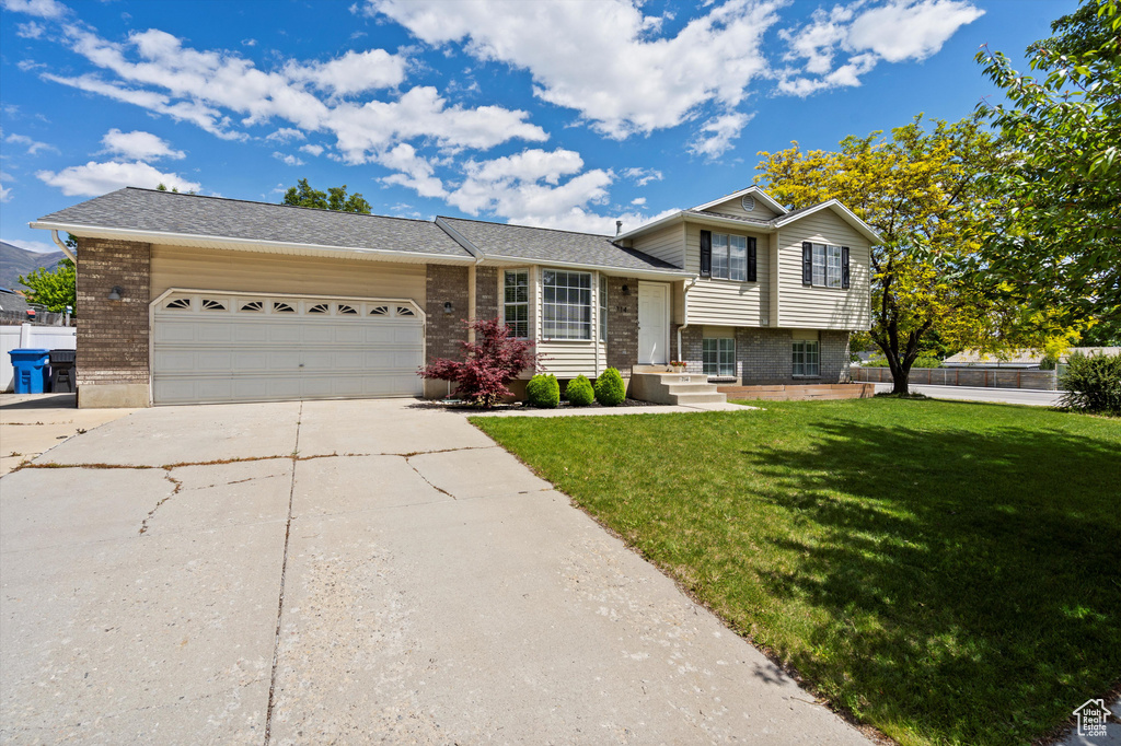 Tri-level home with driveway, brick siding, and an attached garage