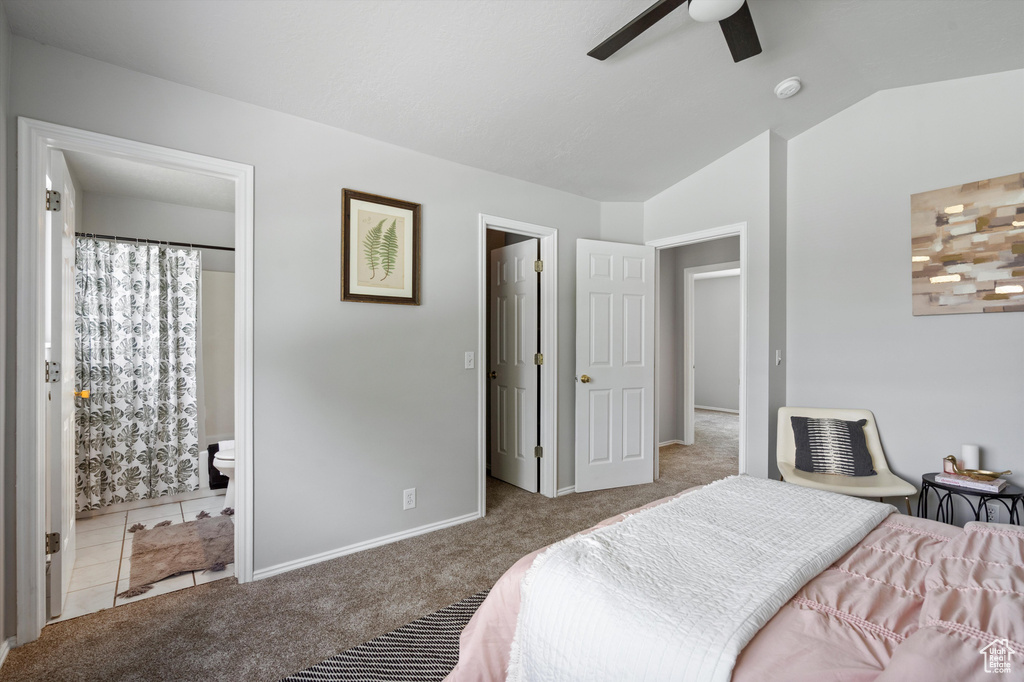 Carpeted bedroom featuring lofted ceiling, ensuite bathroom, and baseboards