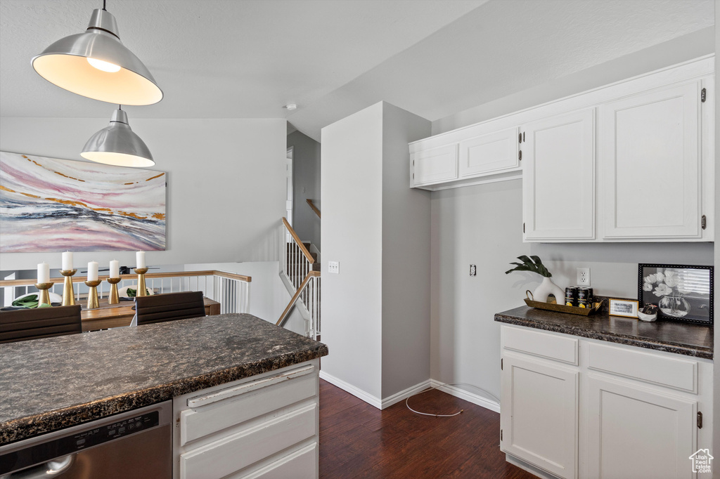 Kitchen featuring stainless steel dishwasher, dark wood-type flooring, white cabinetry, and decorative light fixtures