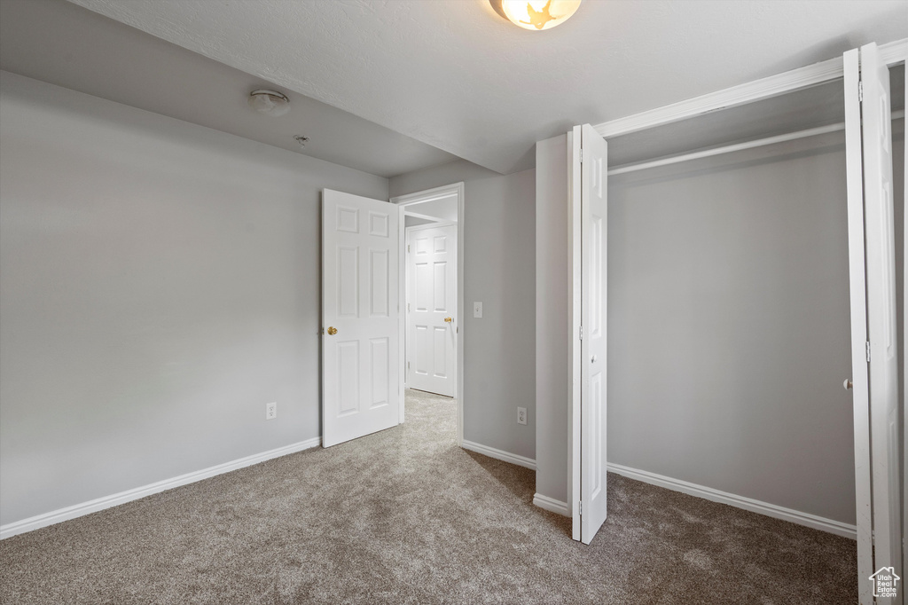 Unfurnished bedroom with carpet, a closet, and baseboards