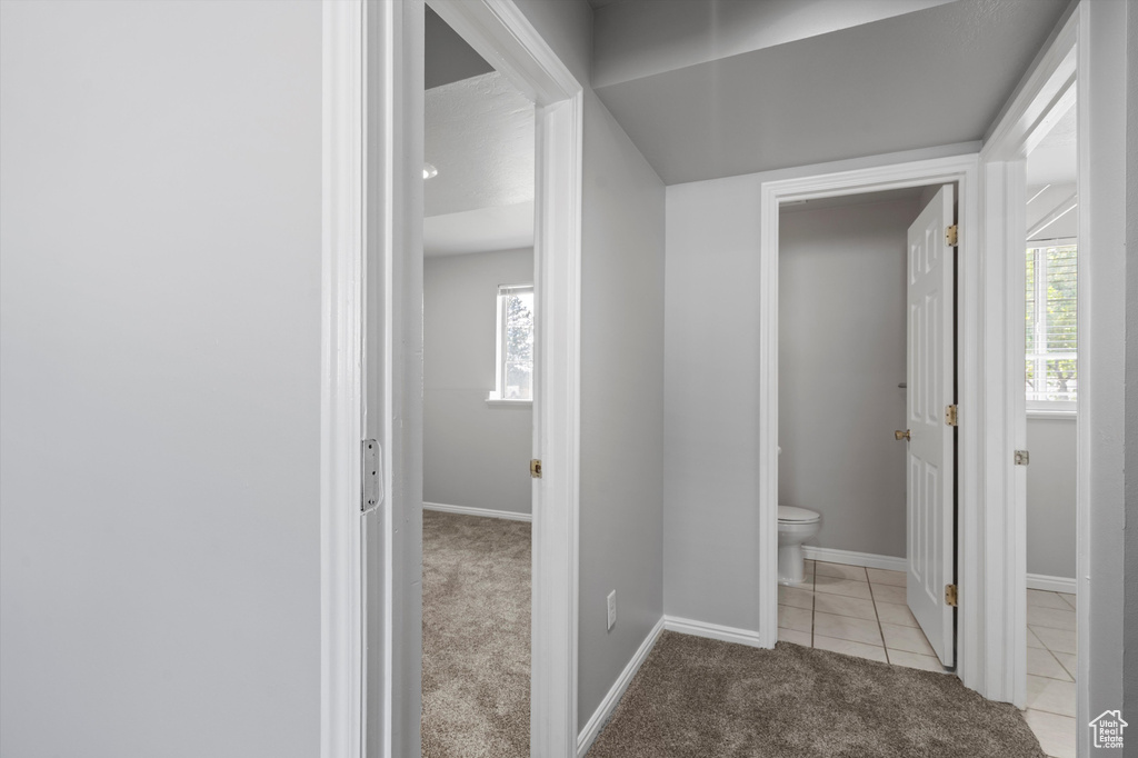 Corridor with light colored carpet, baseboards, and light tile patterned flooring
