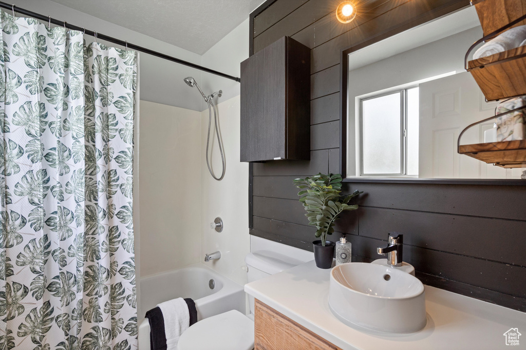 Bathroom with toilet, shower / tub combo with curtain, and vanity