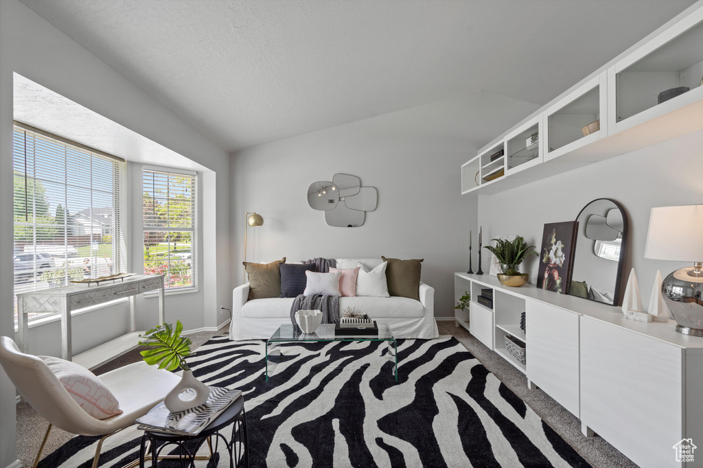 Carpeted living room with lofted ceiling and baseboards