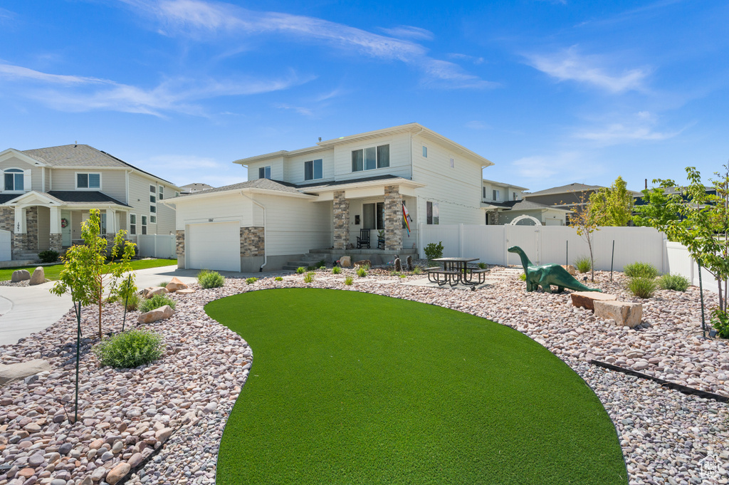 View of front of home with a garage, driveway, and stone siding