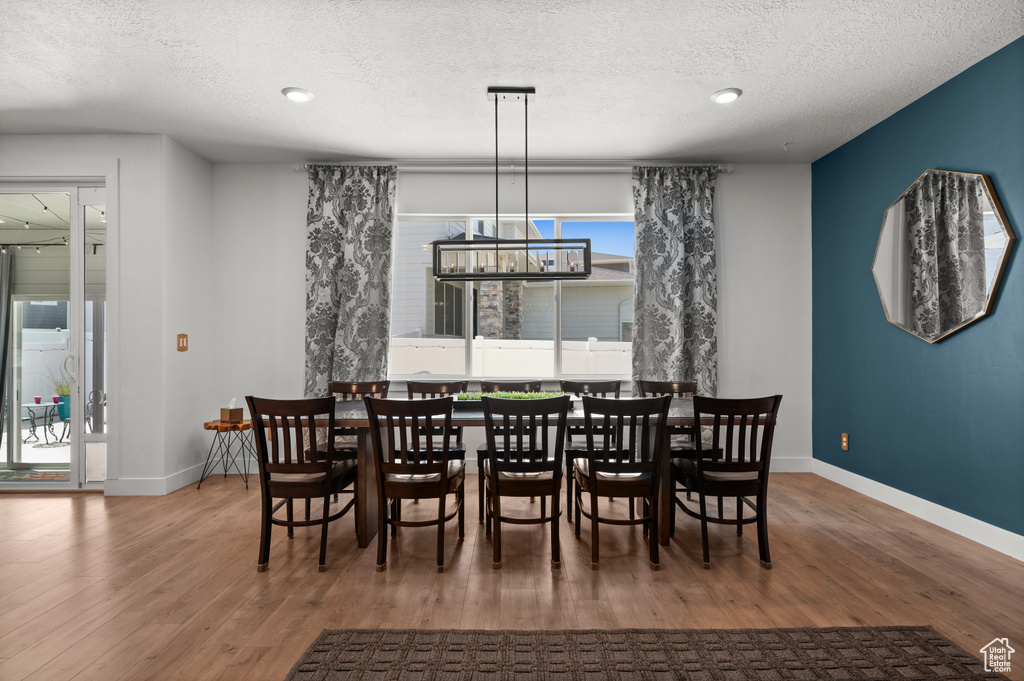 Dining area featuring a chandelier, baseboards, wood finished floors, a textured ceiling, and recessed lighting