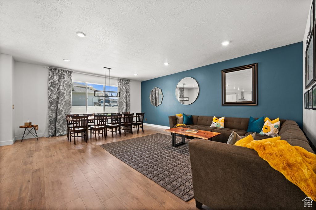 Living room with baseboards, wood-type flooring, a textured ceiling, and recessed lighting