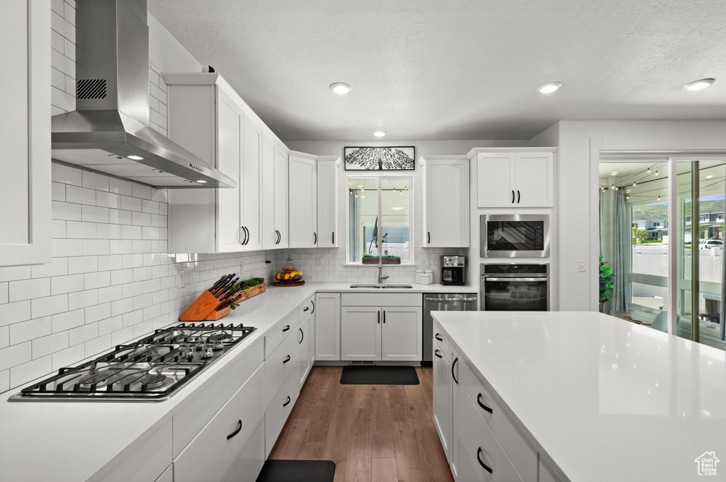 Kitchen featuring appliances with stainless steel finishes, wall chimney exhaust hood, healthy amount of natural light, light countertops, and recessed lighting
