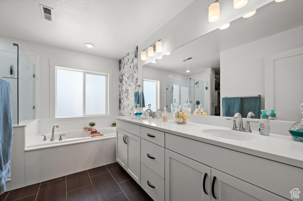 Full bath with a shower stall, double vanity, and a bath