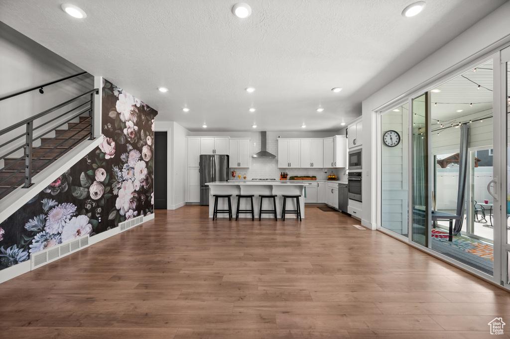 Living area featuring wood finished floors, recessed lighting, stairway, baseboards, and a textured ceiling