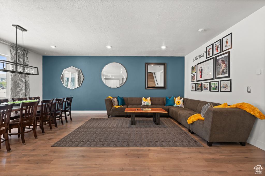 Living area with a chandelier, recessed lighting, baseboards, wood finished floors, and a textured ceiling