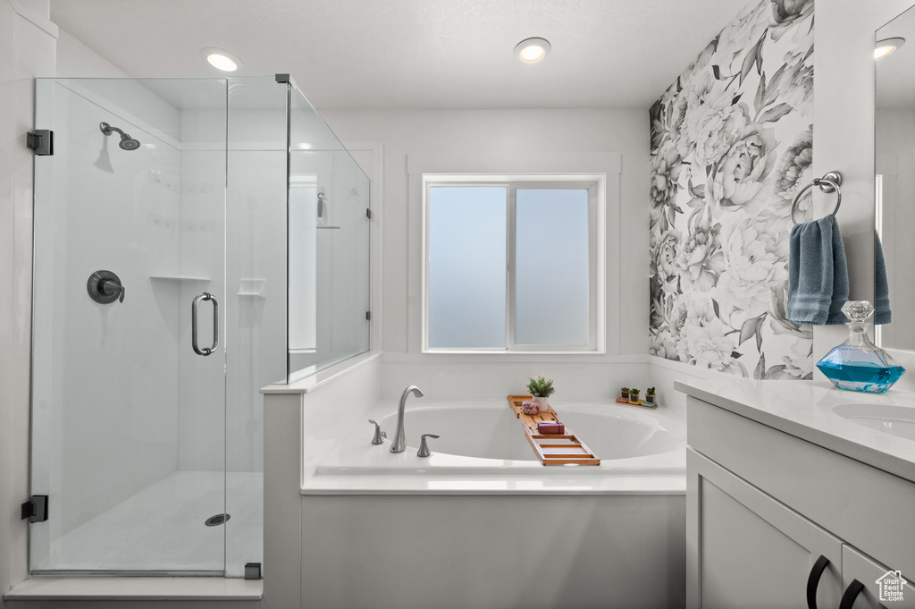 Bathroom with wallpapered walls, a shower stall, a bath, vanity, and recessed lighting