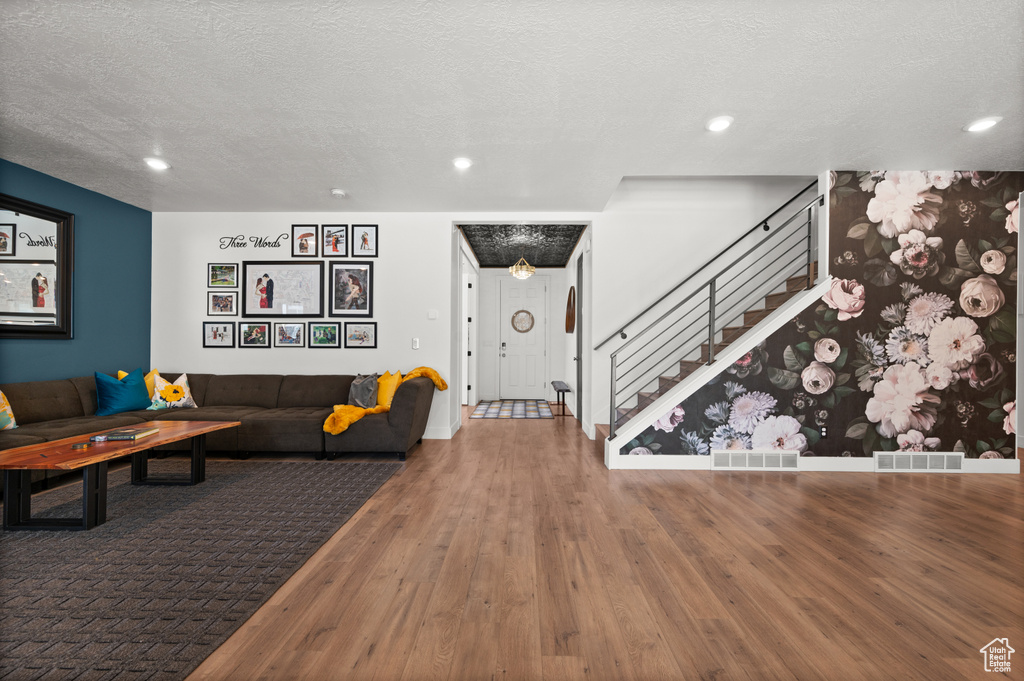 Living room featuring wood finished floors, stairway, a textured ceiling, recessed lighting, and baseboards