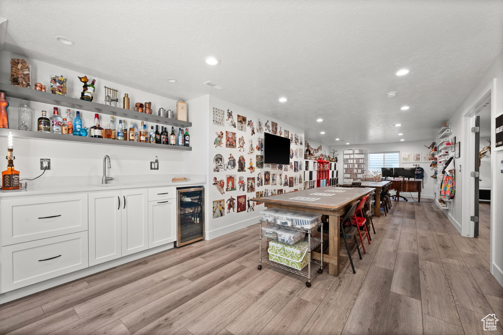 Kitchen featuring beverage cooler, open shelves, recessed lighting, a sink, and light wood-type flooring