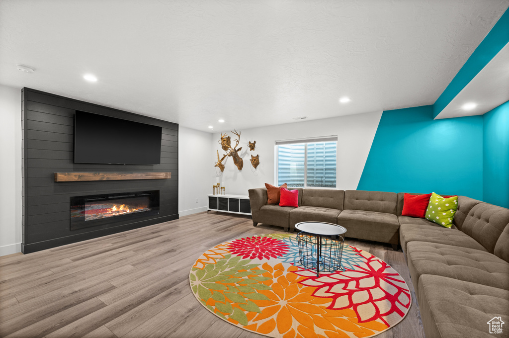 Living area with wood finished floors, baseboards, recessed lighting, and a large fireplace