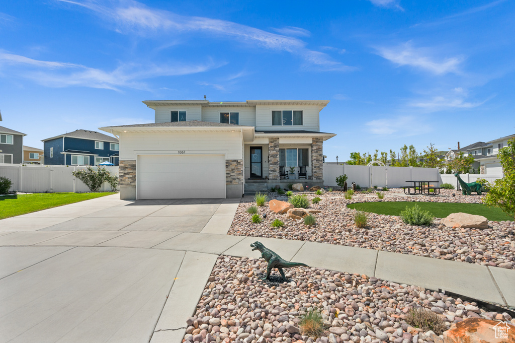 Prairie-style home featuring concrete driveway, stone siding, and an attached garage