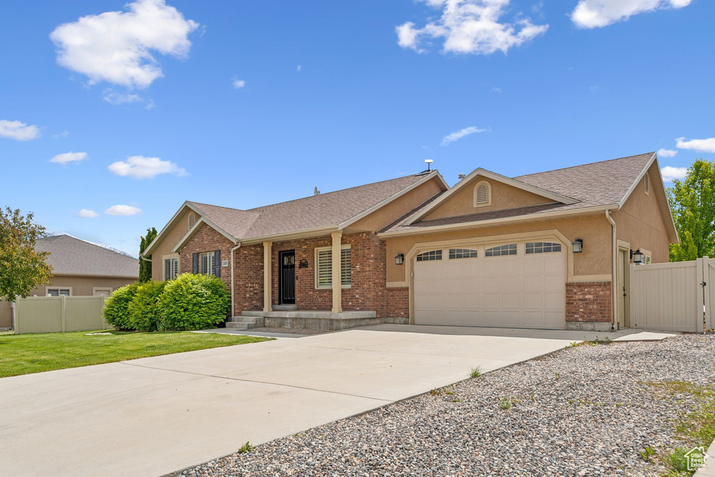 Ranch-style house with brick siding, an attached garage, concrete driveway, a gate, and a shingled roof
