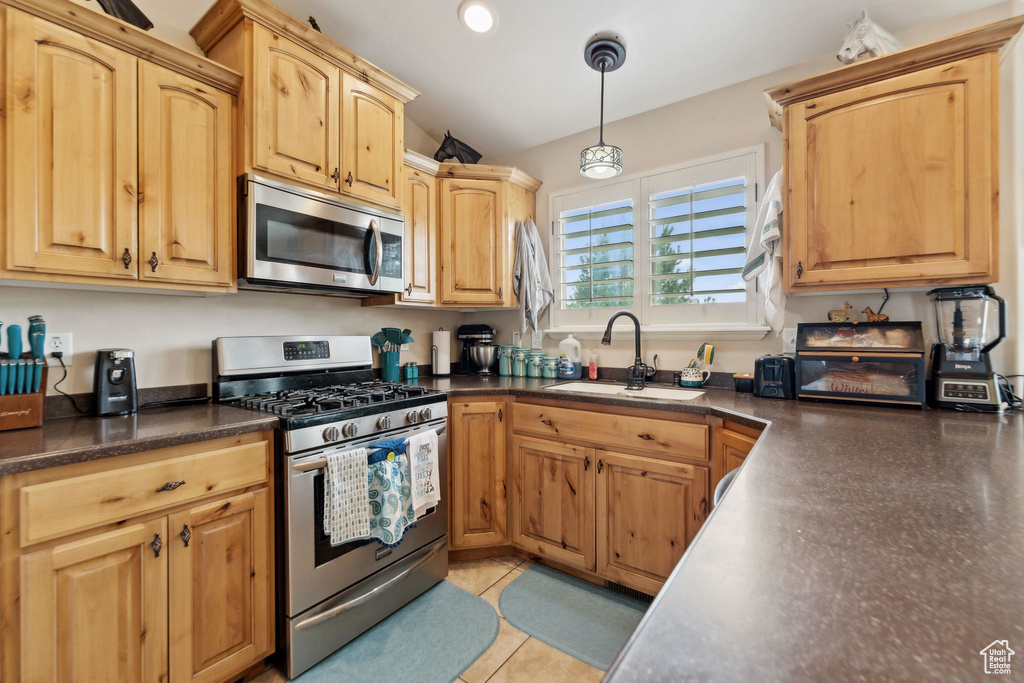 Kitchen with stainless steel appliances, a sink, dark countertops, pendant lighting, and recessed lighting