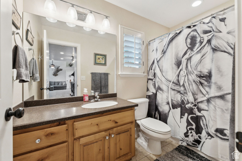 Bathroom featuring vanity, toilet, tile patterned floors, and a shower with shower curtain