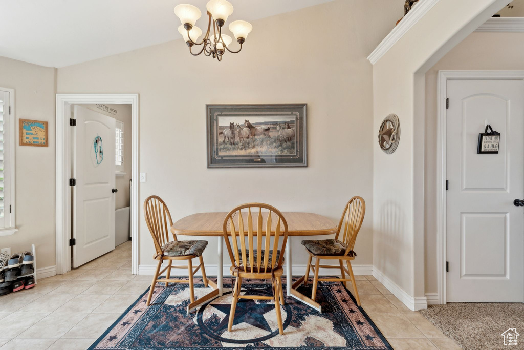 Dining area with light tile patterned floors, a chandelier, lofted ceiling, baseboards, and arched walkways