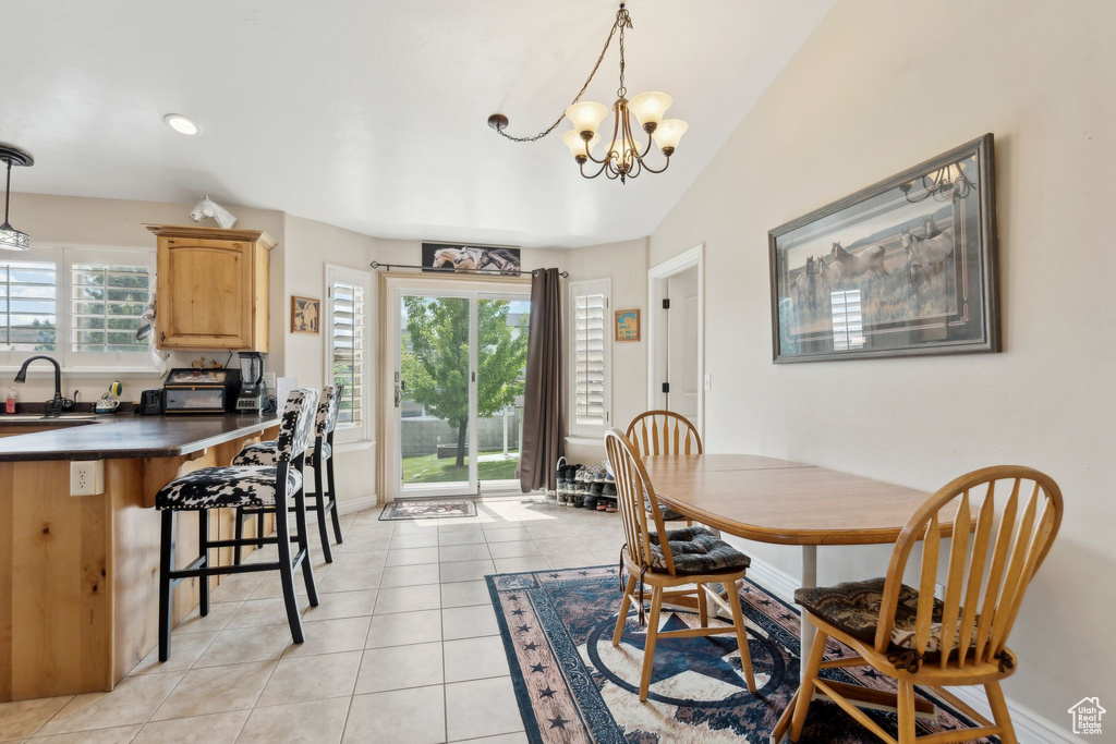 Dining space with a chandelier, light tile patterned floors, and baseboards
