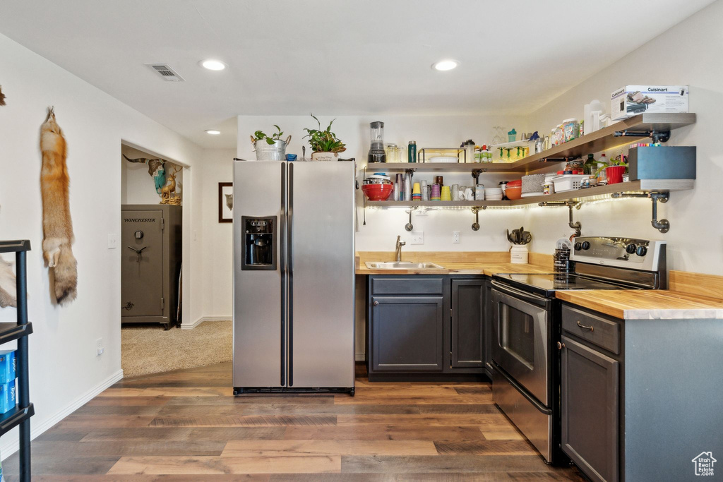 Kitchen with stainless steel appliances, a sink, dark wood-style flooring, butcher block counters, and recessed lighting