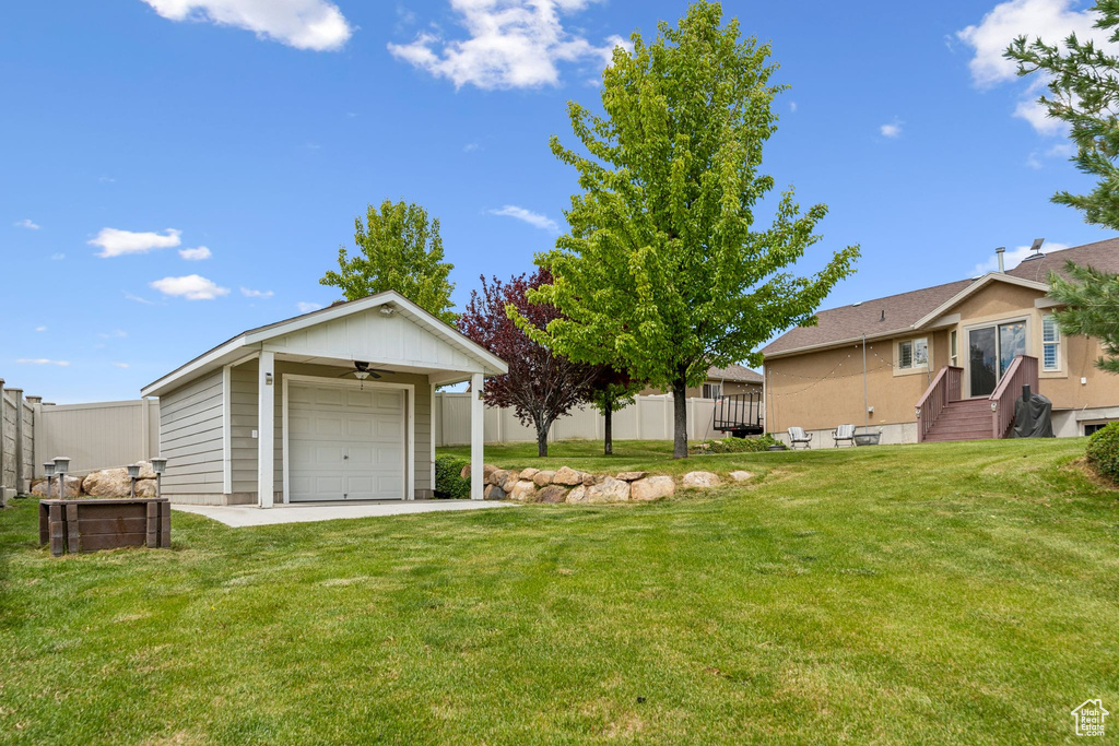 View of yard featuring a garage, entry steps, and a ceiling fan
