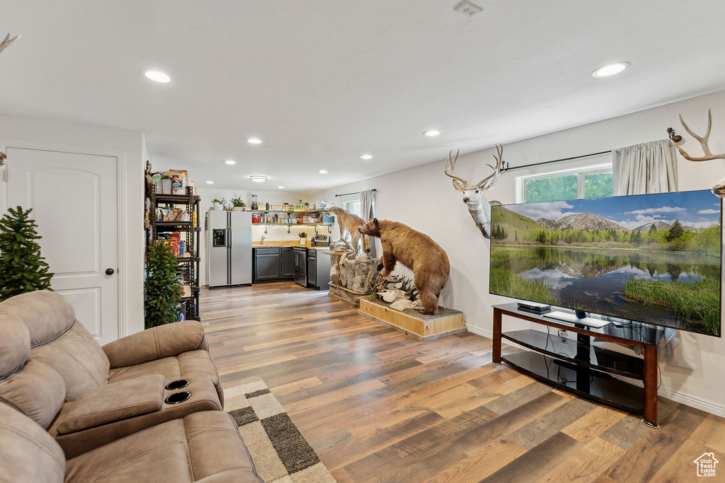 Living room with recessed lighting, light wood finished floors, bar area, and baseboards