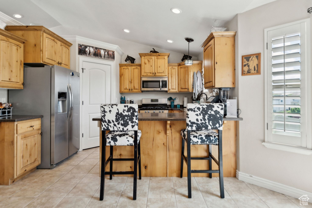 Kitchen with stainless steel appliances, recessed lighting, a kitchen breakfast bar, a peninsula, and light tile patterned floors