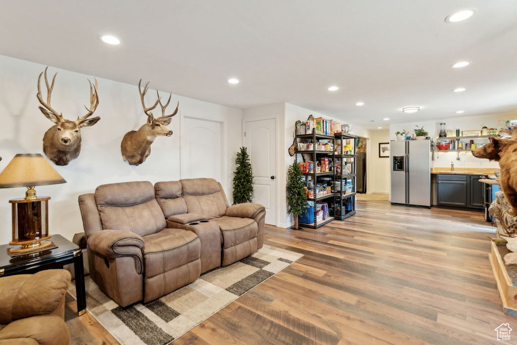 Living area featuring bar with sink, light wood-type flooring, and recessed lighting